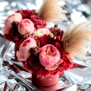 Close-up of two vibrant floral arrangements in red containers on a silver surface